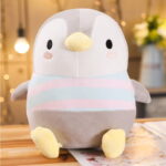A gray chubby penguin plushie with a yellow beak, black eyes, and a striped scarf.