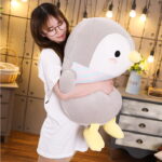 A gray chubby penguin plushie being held by a person.