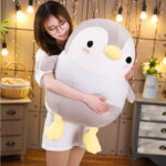 A cute, gray chubby penguin plushie held by a person.