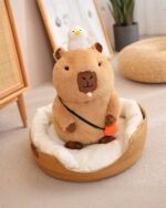 Capybara plushie resting in a woven bed with a duck and carrot toy.