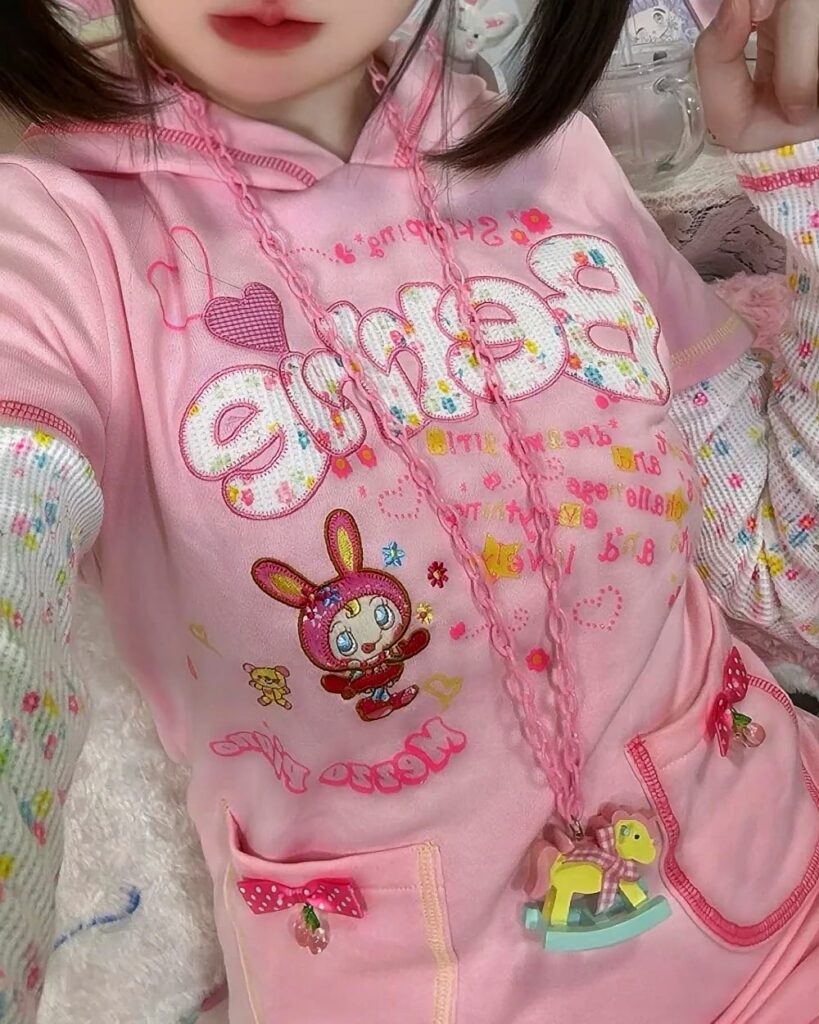 Close-up of a pink pastel hooded dress with cute character graphics.