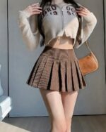 Brown preppy corduroy skirt with pleats, showcasing a fashionable, preppy aesthetic style.