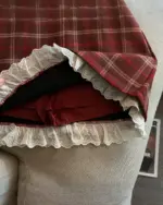 Close-up of a red plaid mini skirt with a white lace hem. This preppy aesthetic skirt features a classic design.