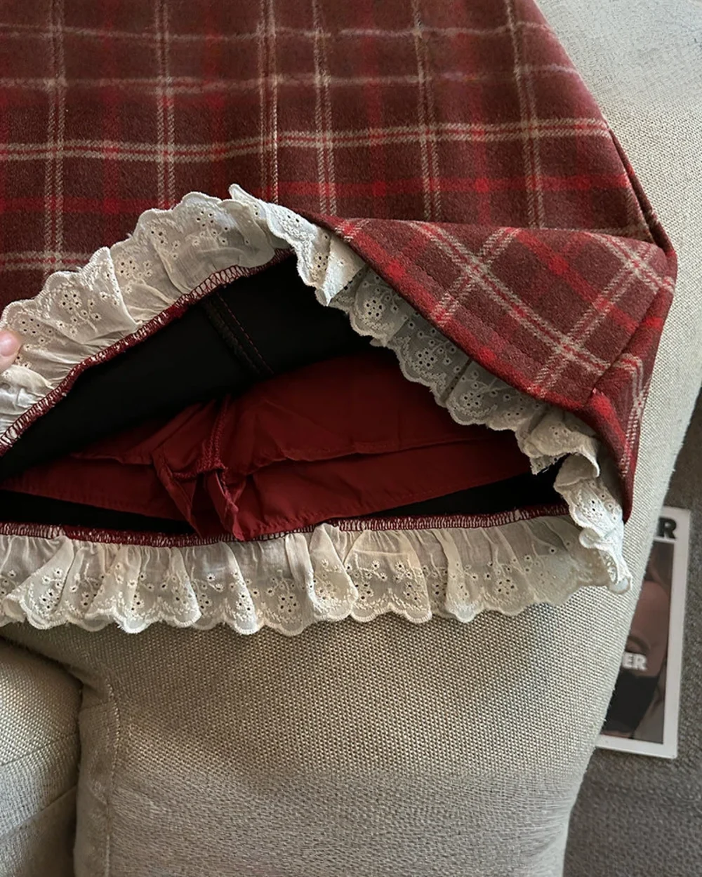Close-up of a red plaid mini skirt with a white lace hem. This preppy aesthetic skirt features a classic design.