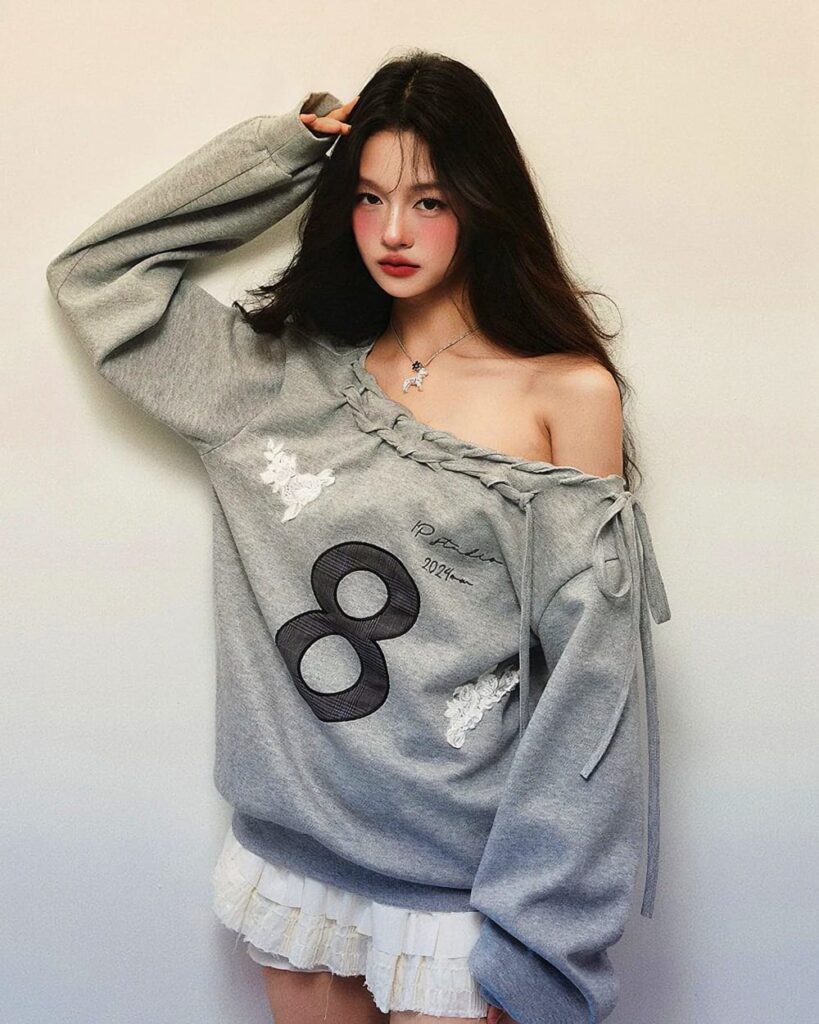 Gray coquette aesthetic sweatshirt worn by a model, featuring an off-shoulder design and floral embroidery.