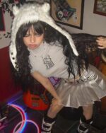 Model wearing a silver pleated skirt with a furry hat and layered clothing.