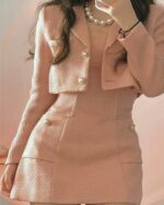 Close-up of a pink retro aesthetic suit with gold buttons and embellishments.