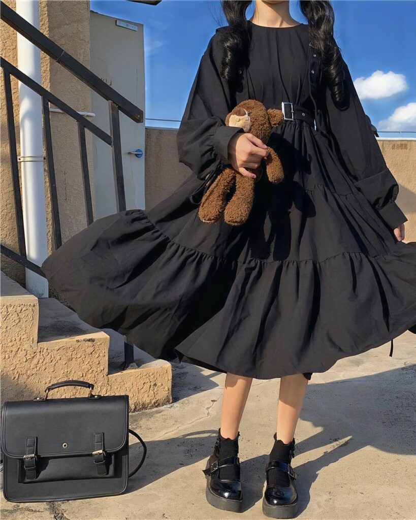Black gothic lolita dress with ruffles, worn by a person outdoors.