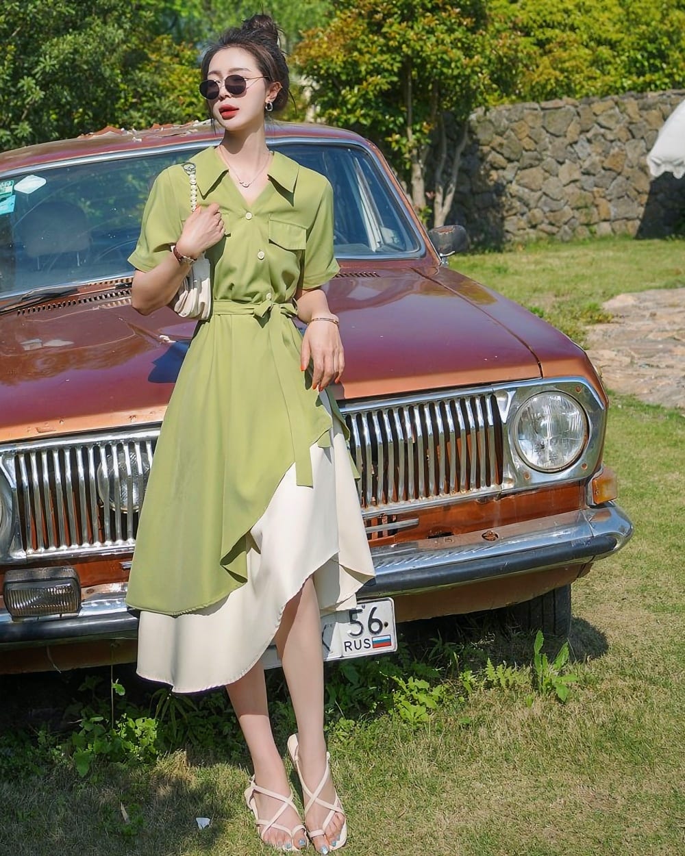 Woman wearing a french vintage dress with a skirt overlay, posing with a vintage car.