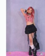 Person wearing a pink rabbit ears hoodie and black ruffled mini skirt, kawaii style outfit.