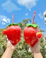 Two kawaii strawberry water bottles with straws and charms, perfect for hydration.
