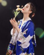 Satin Japanese kimono featuring blue and white floral design, worn by a woman.