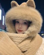 Person wearing a beige fox ears scarf and hooded winter hat.