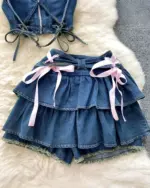 Two-piece coquette denim set featuring a ruffled skirt and cropped top with tie details.