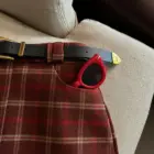 Close-up of a red preppy aesthetic skirt with a plaid pattern and accessories.