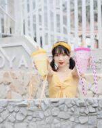 Two kawaii fruit bottles, featuring a lemon and strawberry design, are held by a person outdoors.