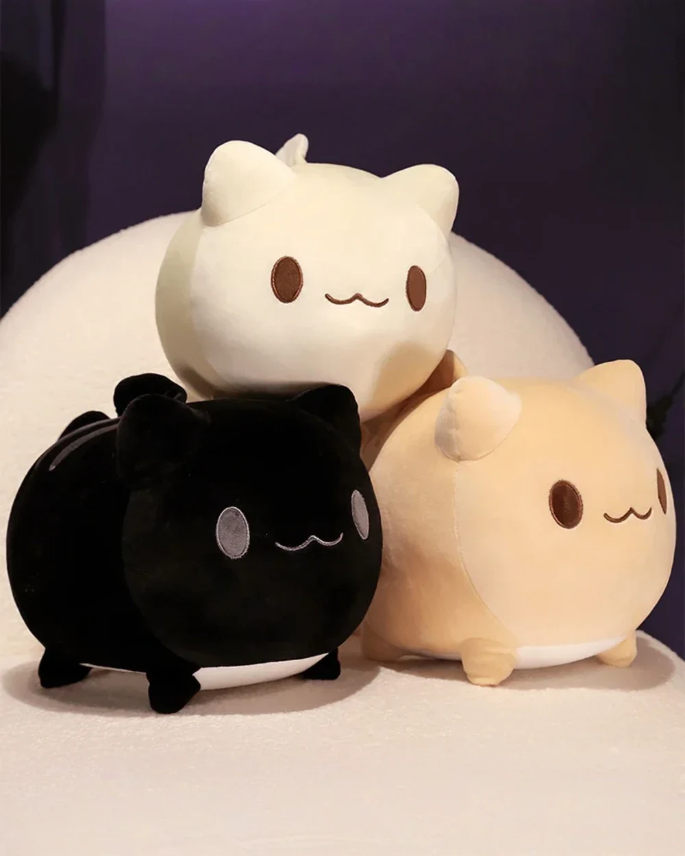 A set of round neko plushies in black, beige, and white. These round neko plushies are soft and cute.