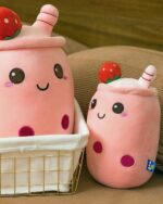Two pink boba milk tea plush toys, one large and one small, with strawberry accents and stitched details.