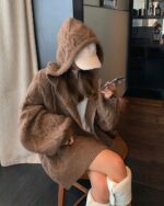 Brown pastel hooded sweater featuring a fluffy hood and zipper detail, worn by a person indoors.