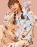 Woman wearing Strawberry Lamb kawaii pajamas with a plush lamb and strawberries.