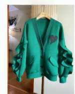 Green lace cardigan kawaii with a heart applique and ruffled sleeves, hanging on a hanger.