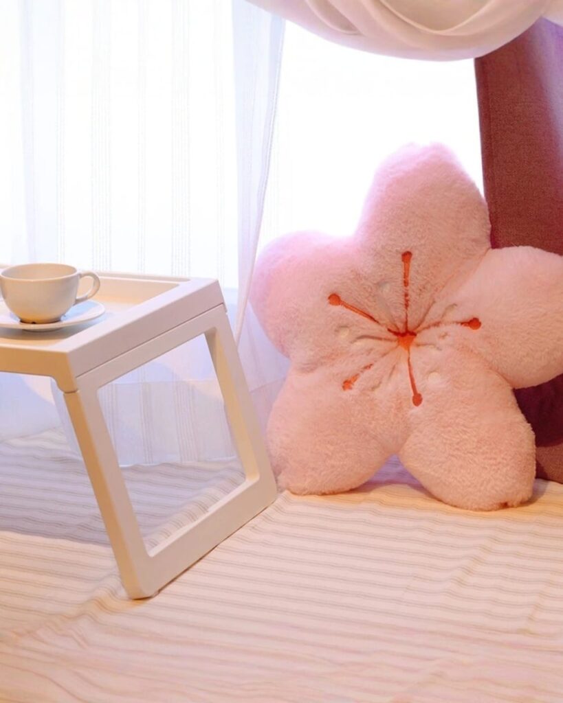 Pink cherry blossom pillow decorative cushion on a bed with a tray and cup.