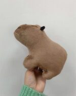 Brown capybara plushie held in hand against a white background.