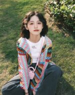 Retro knitted cardigan featuring a colorful, hand-knitted design worn by a woman outdoors.