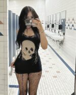 Model wearing a black gothic aesthetic dress with a large skull print.