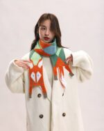 Woman wearing a Cute Fox Scarf with blue and orange fox design, styled with a white coat.