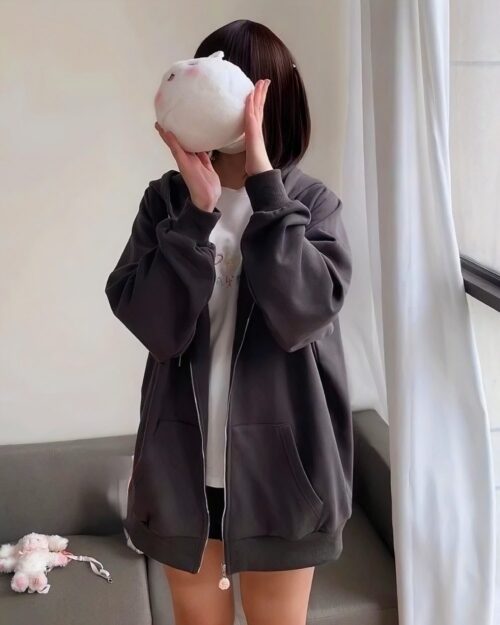 Model wearing a gray cat eared hoodie, with a plush toy nearby.