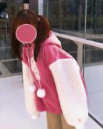 Person wearing a pink kawaii lamb hoodie with a fluffy collar and pom-pom.