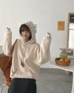 Cream-colored ethno-chic hoodie with embroidered detailing and tassels. Casual fashion style.