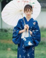 Woman wearing a deep blue yukata with floral pattern, holding an umbrella.