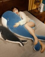 Blue kawaii whale plushie, Bubbles, lying on a bed, soft and cuddly.
