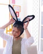 A person wearing a kawaii bunny ears hat, black headband with large plush bunny ears.