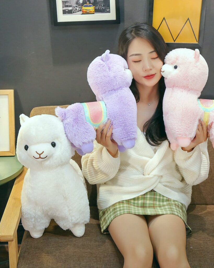 Colorful alpaca plush toys in purple, pink, and white. Andean Edition plush collection.
