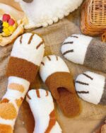 Cute brown and white cat paw slippers displayed with other cozy items.