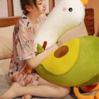 A plush banana duck plushie resting on a rug, held by a person.