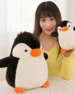 A large, soft chonky penguin plushie toy with orange beak and feet.