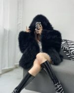 Black puffy hooded coat worn by a person indoors. Warm winter fashion.