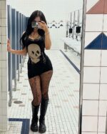 Woman wearing a skull printed tight gothic aesthetic dress and black boots.