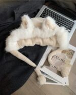 Close-up of a plush fox ears hat lying on a magazine and beside a laptop.