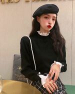 Close-up of a french aesthetic top, showcasing ruffled detailing and a pearl necklace.