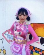 A person wearing a pink y2k animecore shirt and matching accessories, posing outdoors.