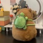 Brown capybara plushie sitting with a green turtle backpack.