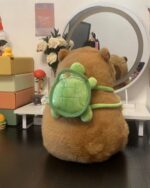 Brown capybara plushie sitting with a green turtle backpack.