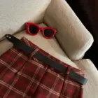 Red plaid mini skirt with black belt and sunglasses, showcasing a preppy aesthetic.
