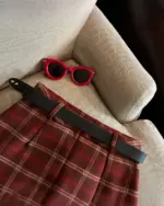 Red plaid mini skirt with black belt and sunglasses, showcasing a preppy aesthetic.