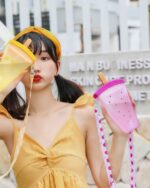 A pink kawaii fruit bottle with a carrying strap, featuring a fruit design.